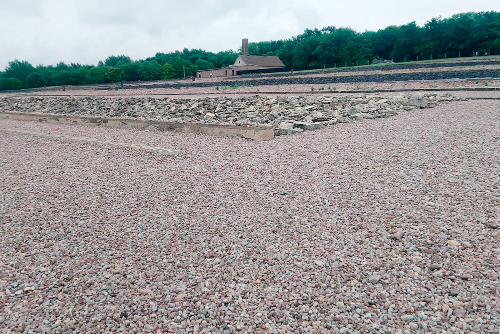 Бухенвальд сейчас выглядит так. Когда его превратили в мемориал, места бараков обозначили камнями. На заднем плане видно здание крематория. По работе я оказывалась в этих местах больше десяти раз, и там всегда была промозглая погода. Жуткое место