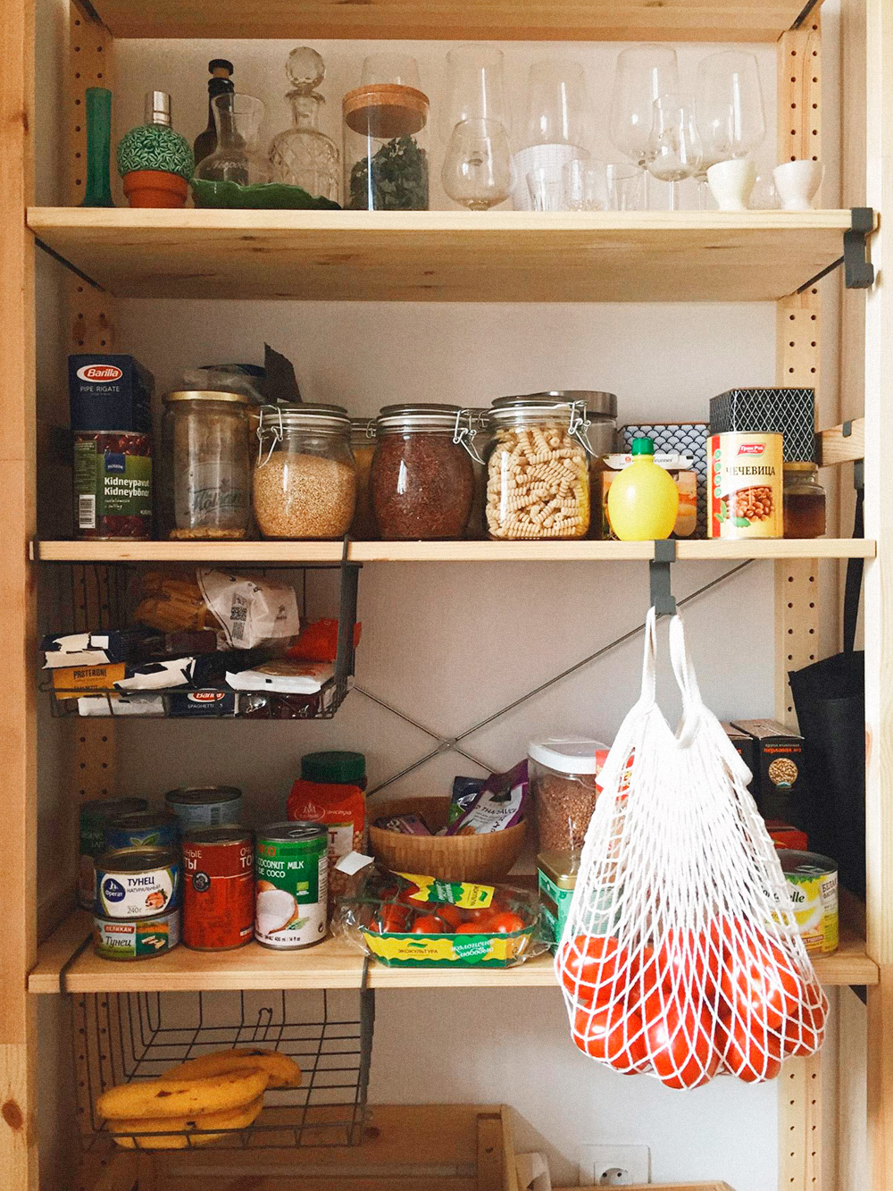 Новый стеллаж с запасом продуктов: мука, сахар, гречка, белый и бурый рис, фасоль, нут и чечевица — сухие и консервированные, несколько видов пасты и лапши, кускус и булгур, тунец и резаные томаты в банках, кокосовое молоко, приправы и соусы