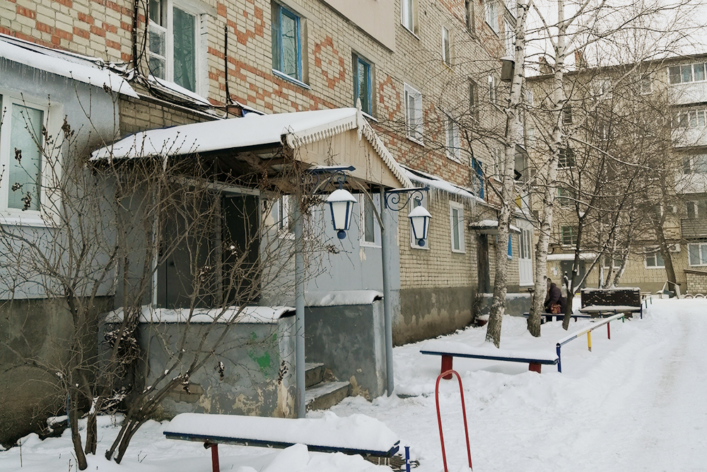 Дом, в котором расположена квартира. Вход в подъезд украшен фонарями, а на козырьке — резьба