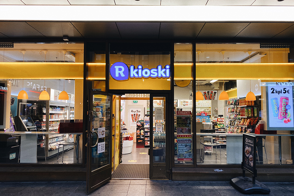 Один из R-kioski в Хельсинки, по всей Финляндии их более 700. Помимо снеков и газетной продукции, в каждом таком киоске можно купить билеты на общественный транспорт, лотерейные билеты, лицензии на рыбалку и предоплаченные симкарты. Некоторые точки оказывают почтовые услуги. Также жители Финляндии могут получать в ближайшем к дому киоске паспорта и ID-карты, оформленные онлайн