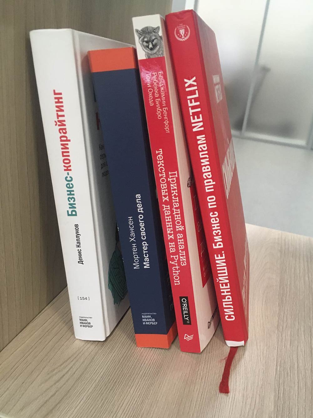 Одна из полок стеллажа с книгами на работе
