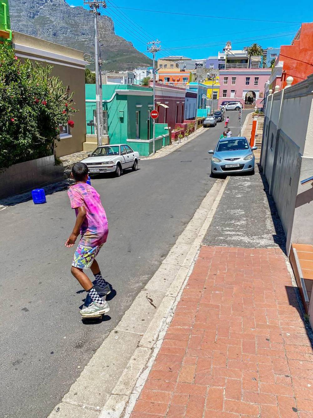 На улицах обычная жизнь: мальчик катается на скейте в Малайском квартале в Кейптауне