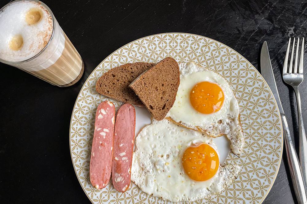 Завтрак: глазунья, сосиска, хлеб, пирожное, кофе