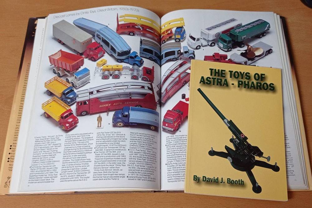 Открытая книга — The&nbsp;collector's all-colour guide to transport toys, а маленькая на ней — переизданный каталог фирмы Astra Pharos