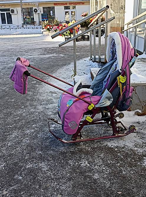 Санки-коляска имеют накидку и капюшон, поэтому ребенку будет комфортнее и теплее. А еще есть возможность разложить сиденье — тогда малыш сможет спать на прогулке