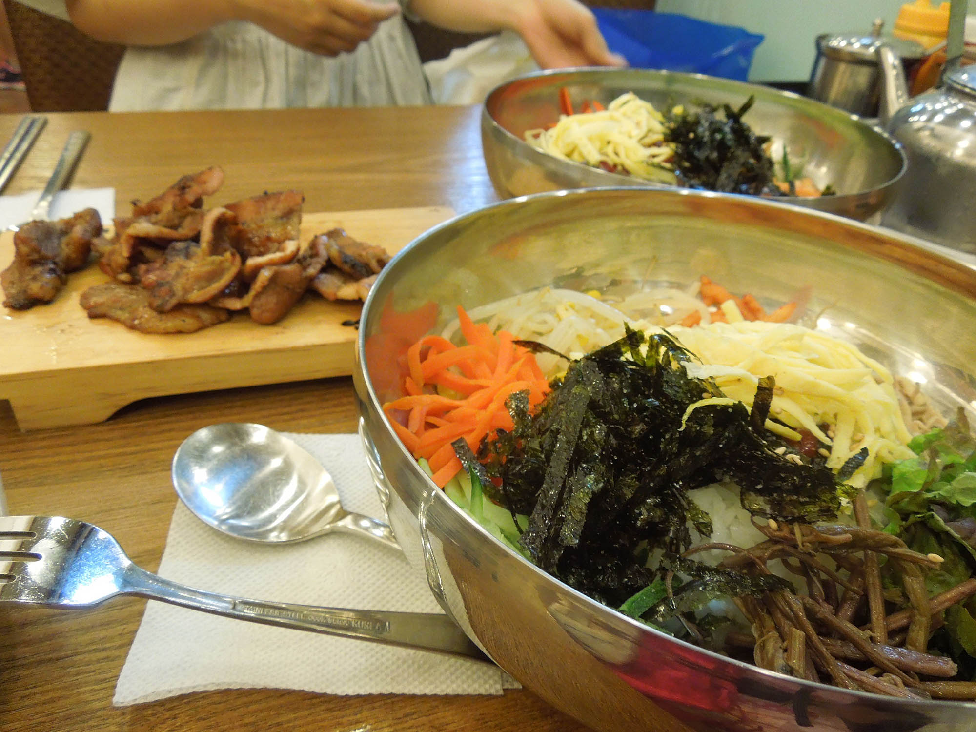 В глубокой тарелке рис с мясов и овощами — пибимпап, а на дощечке мясо, жаренное на гриле, — пулькоги