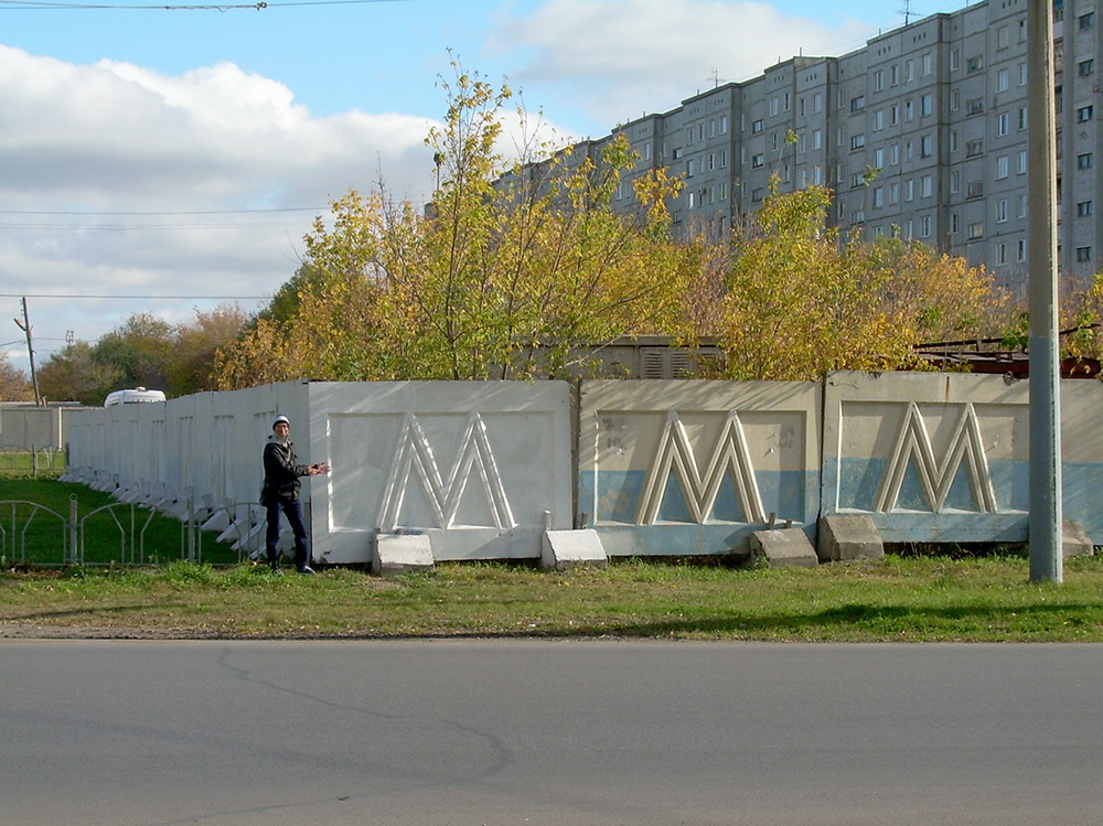 Этот забор поставили возле моего дома 26 лет назад, когда начали строить омское метро. Тогда я ходил в начальную школу и думал: «Ждать метро придется долго. Наверное, я уже школу к тому времени буду заканчивать». За годы стройки такие заборы с буквой «М» ставили и убирали в разных частях города, директор компании-подрядчика отсидел и вышел, причем по другому делу. В этом году правительство Омской области решило прекратить строительство — забор начали сносить