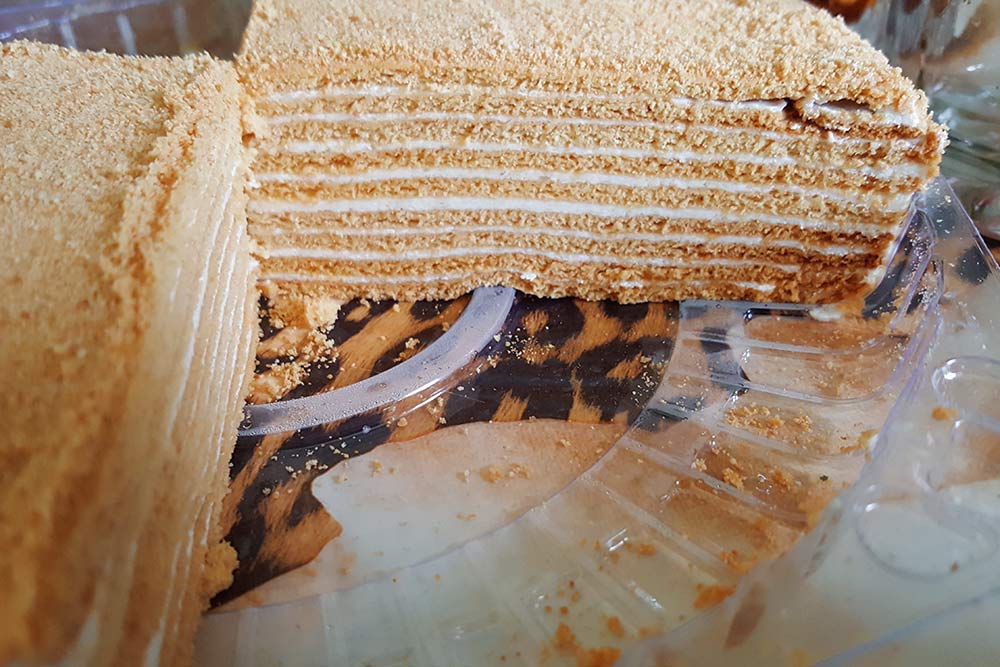Разрез торта «Рыжик». Он непохож на популярные классические торты по вкусу или текстуре. У «Рыжика» нежный сливочный крем прослаивает многочисленные тонюсенькие рассыпчатые коржи. Можно сравнить его с миксом классических тортов «Наполеон» и «Медовик»